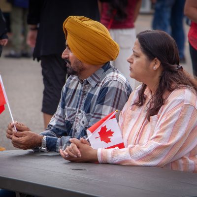 Sikh husband and wife holding flags during a Canada Day event.