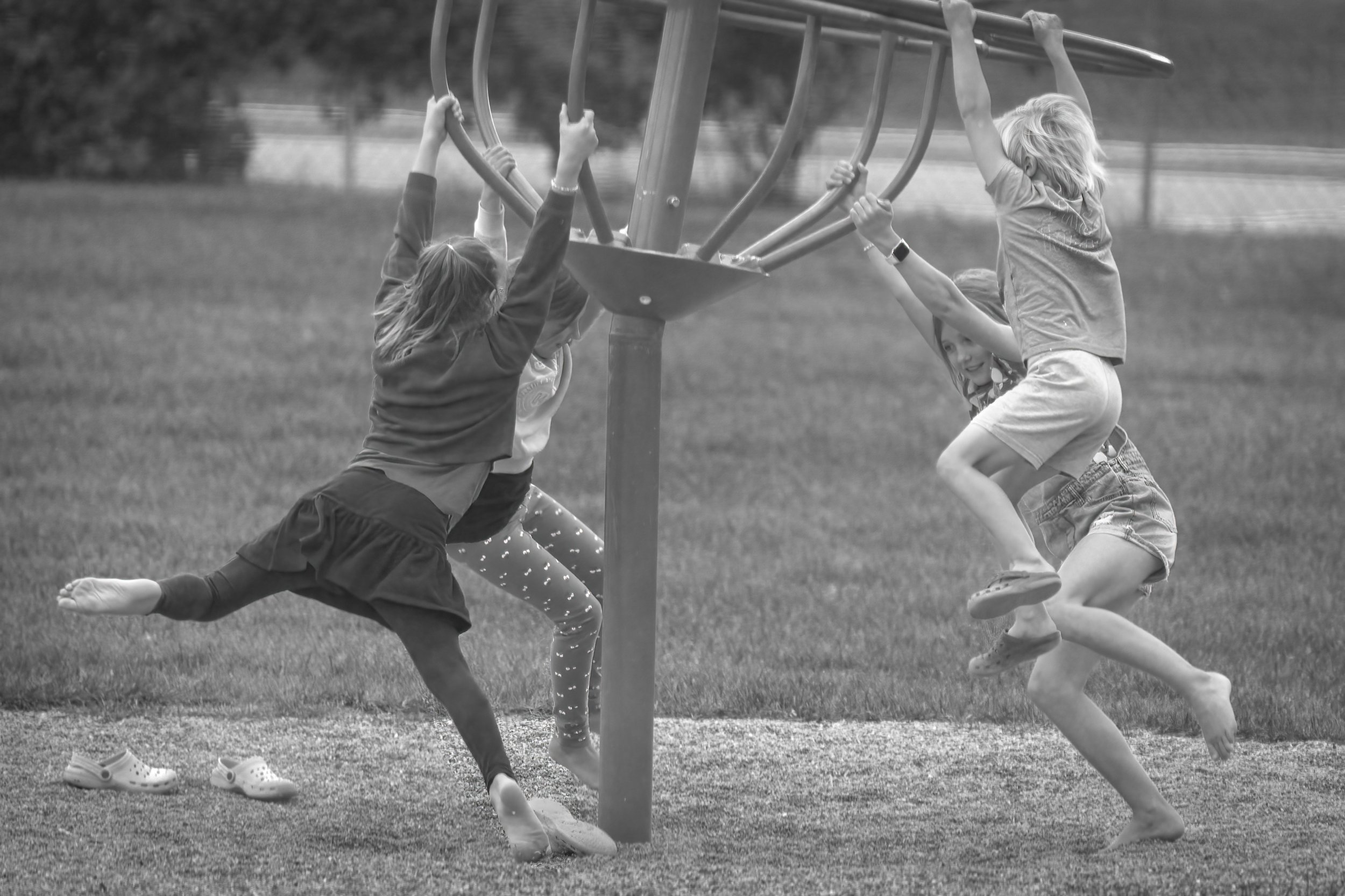 Children spinning on rotary monkey bars in a a playround.