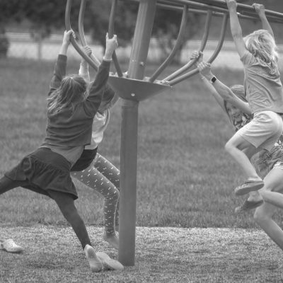 Children spinning on rotary monkey bars in a a playround.