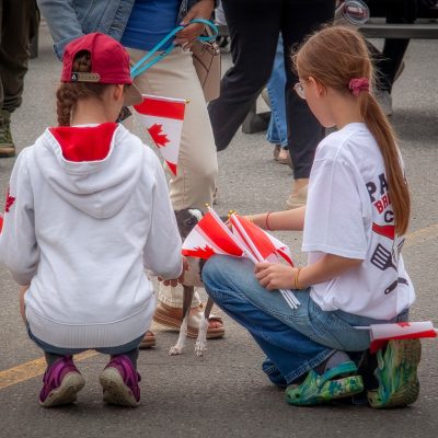 Two young girls kneeling to pet a puppy.