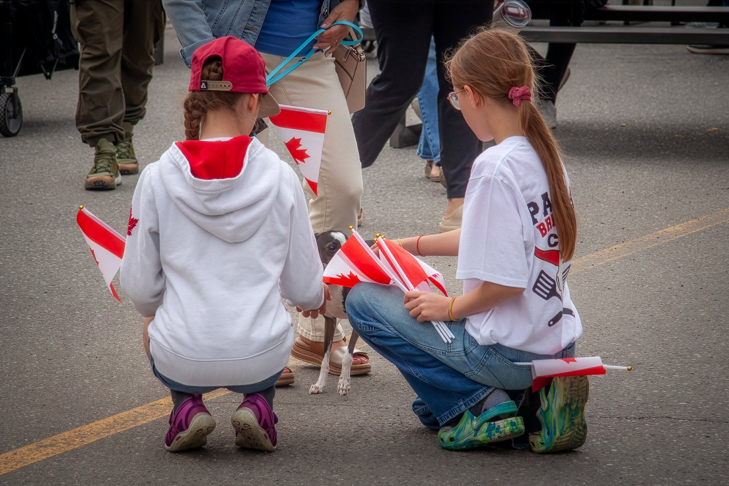 Two young girls kneeling to pet a puppy.